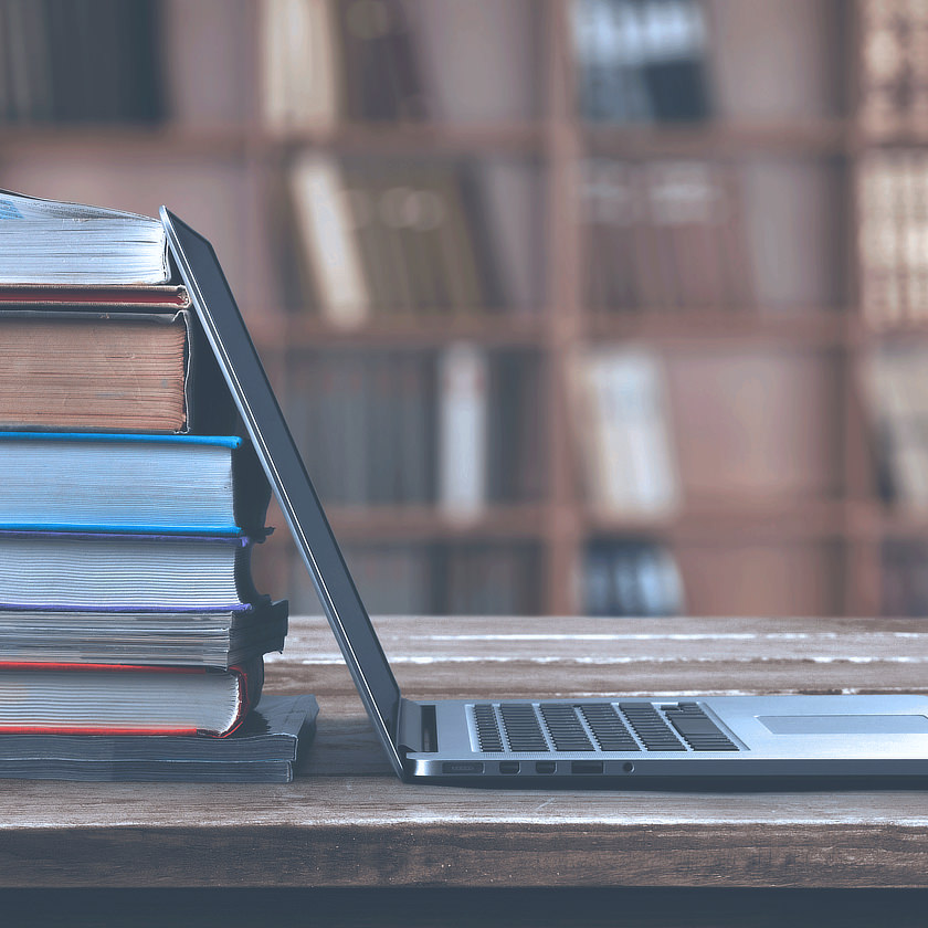 Photo: Laptop and a stack of books in a library