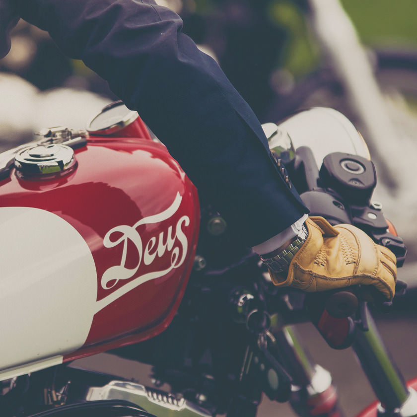 Photo: Crop of a motorcycle with man's gloved hand on handlebar